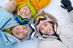 快乐的一家三口放松的躺在雪地上
