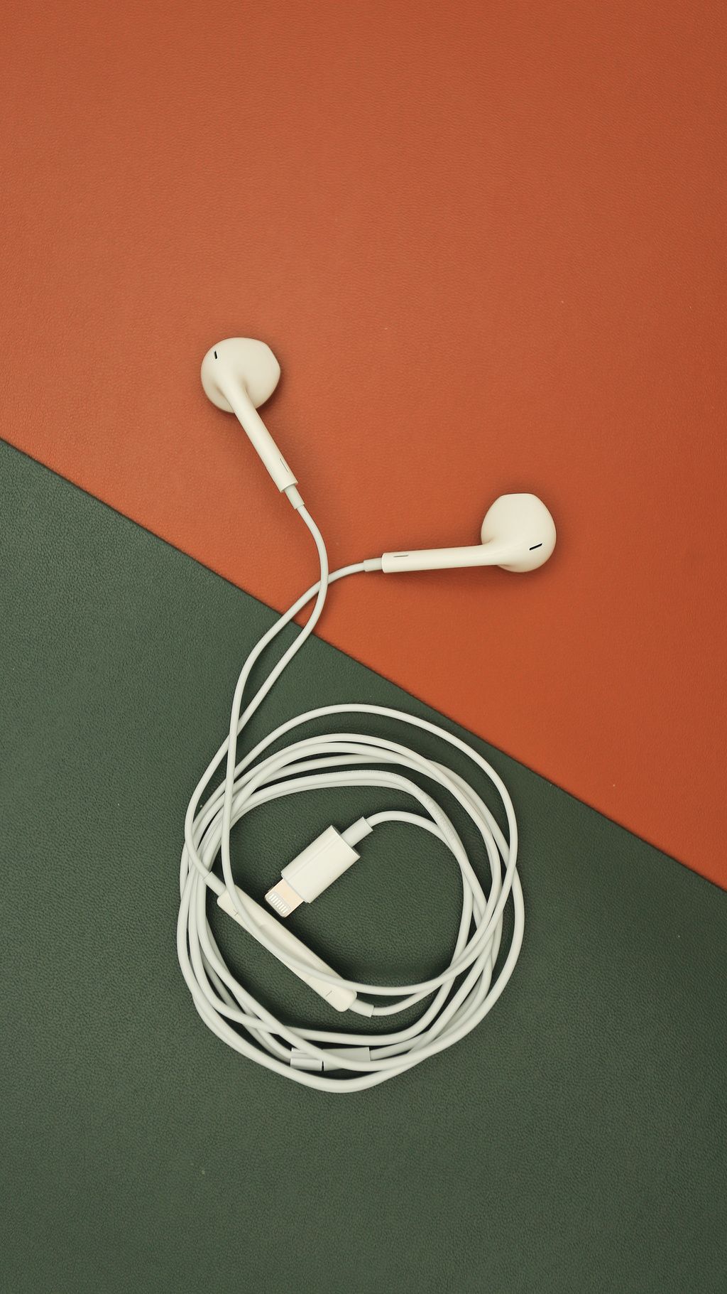 橙色和绿色背景上的白色有线耳机