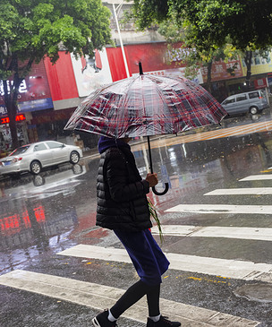 下雨天街道打伞匆匆行走的游客