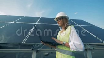 女建筑工人正带着电脑沿着太阳能电池板行走