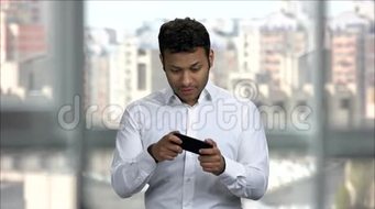 兴奋的印度男人用智能手机玩网络游戏