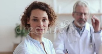 健康微笑的欧洲女人坐在医生面前看着摄像机
