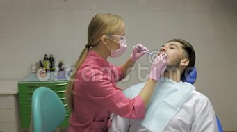 女性牙医男性病人在牙科中清洁牙齿