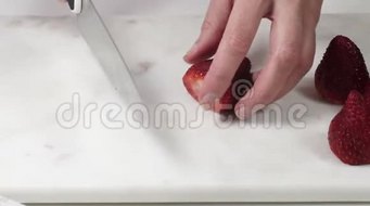 在白色背景的大理石切割板上切割草莓