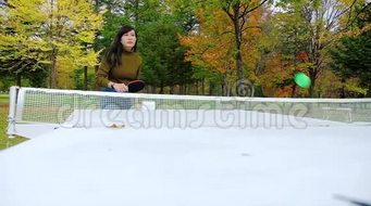 一个快乐的女人在公园打乒乓球或乒乓球秋天