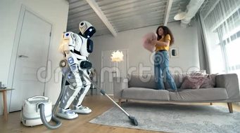 年轻女人玩枕头而白色机器人做真空清洁